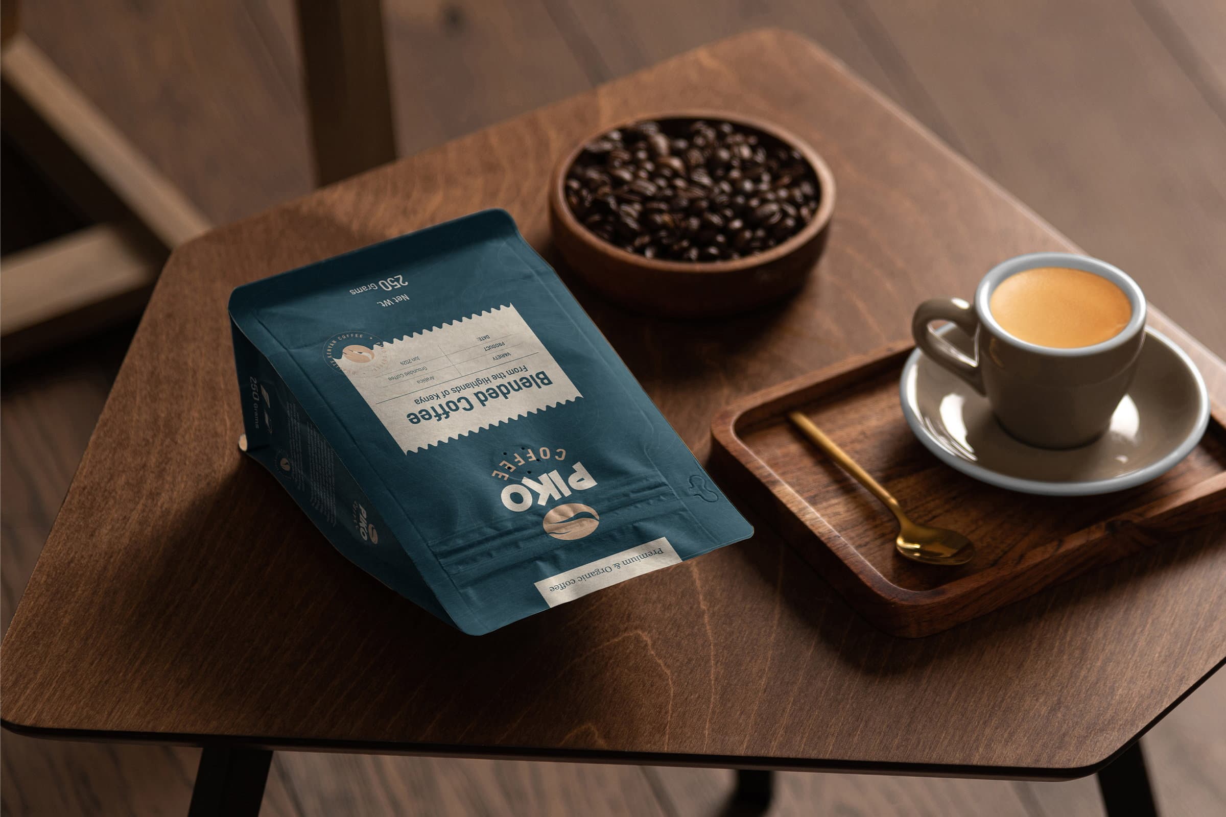 A Piko Coffee pouch on a dark wooden table beside a bowl of roasted beans and an espresso served on a wooden tray.